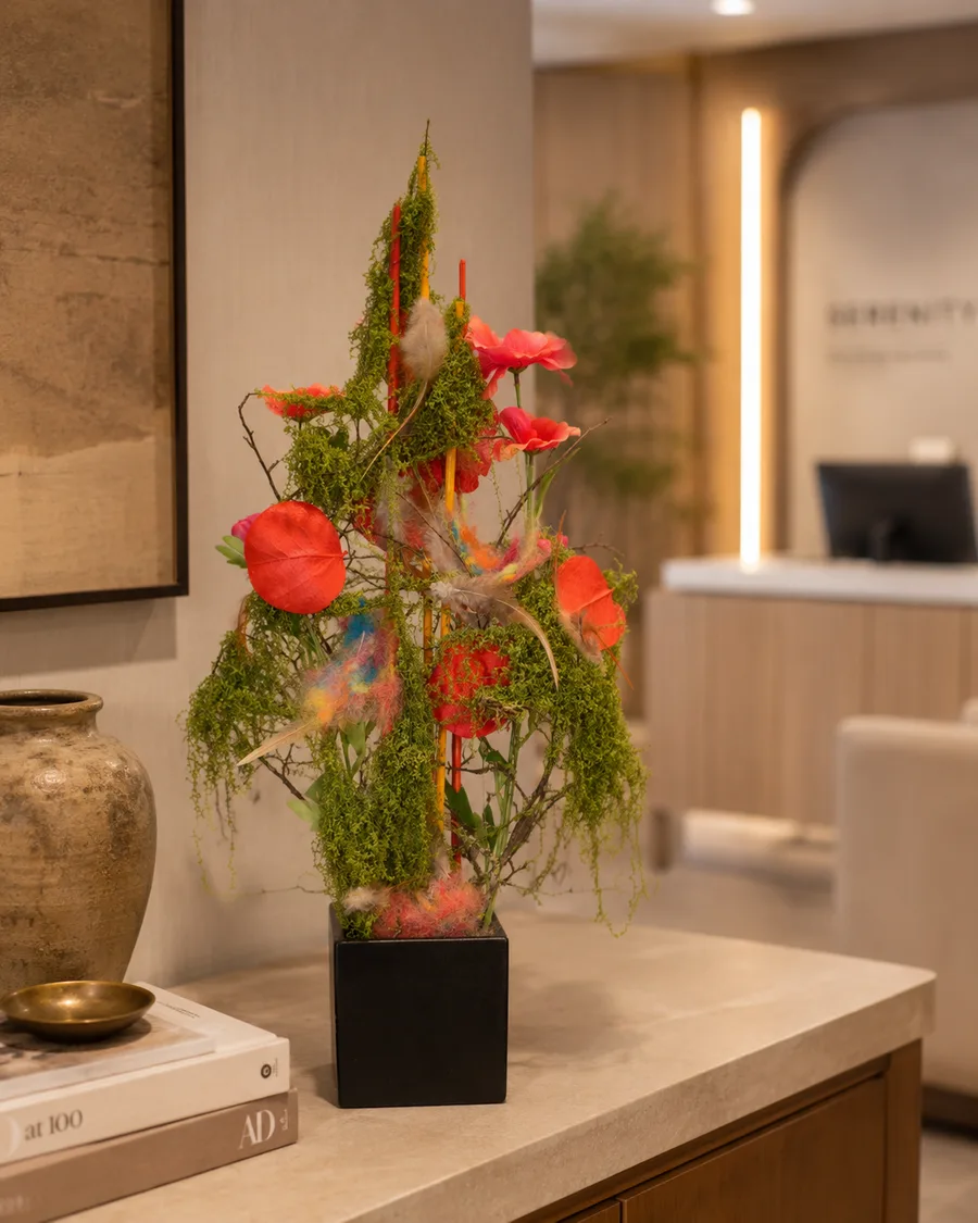 Florales Gesteck mit roten Anthurien, Moos und farbigen Fasern in einem Empfangsbereich